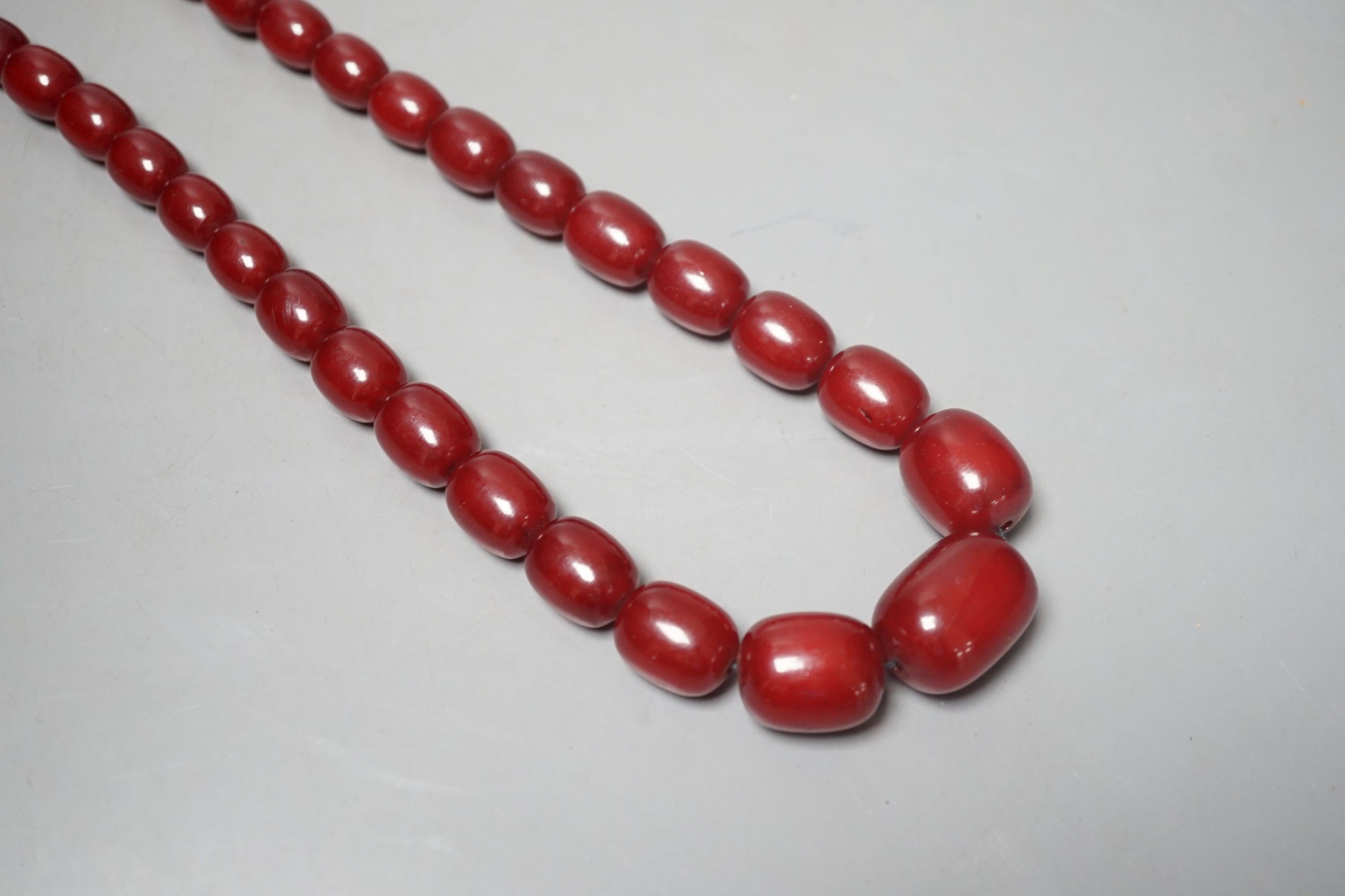 A single strand graduated oval simulated cherry amber bead necklace, 78cm, gross weight 121 grams.